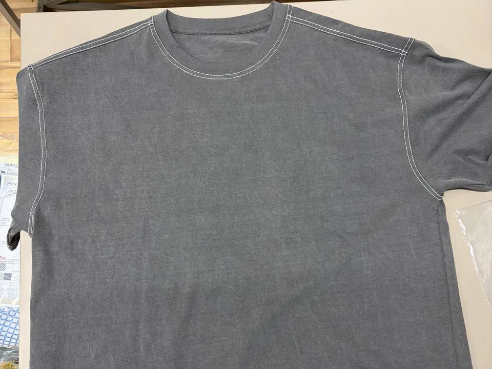 Close physical detail of the grey SO-CT-001 first sample, showing the neckline, shoulder, and contrast topstitching.