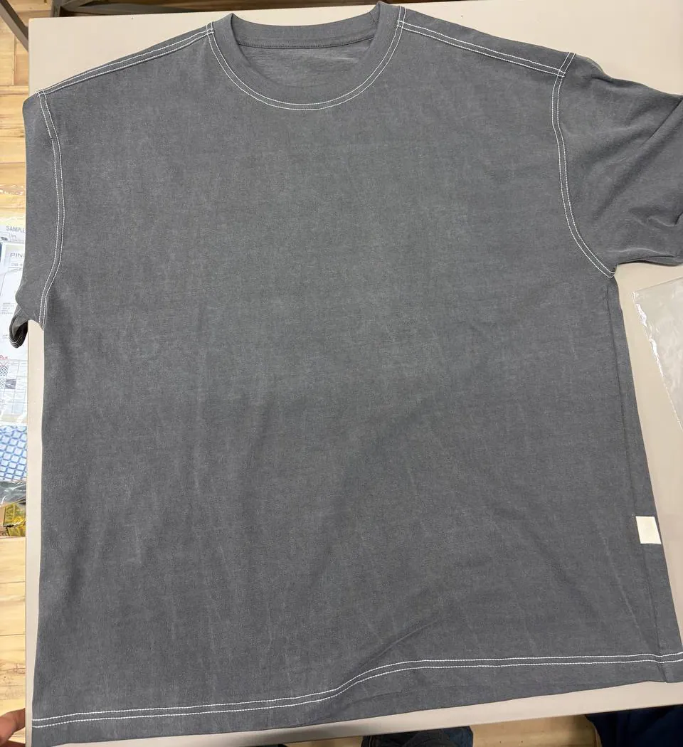 Cropped physical record of the grey short-sleeve T-shirt first sample laid flat, showing the full body and contrast topstitching.